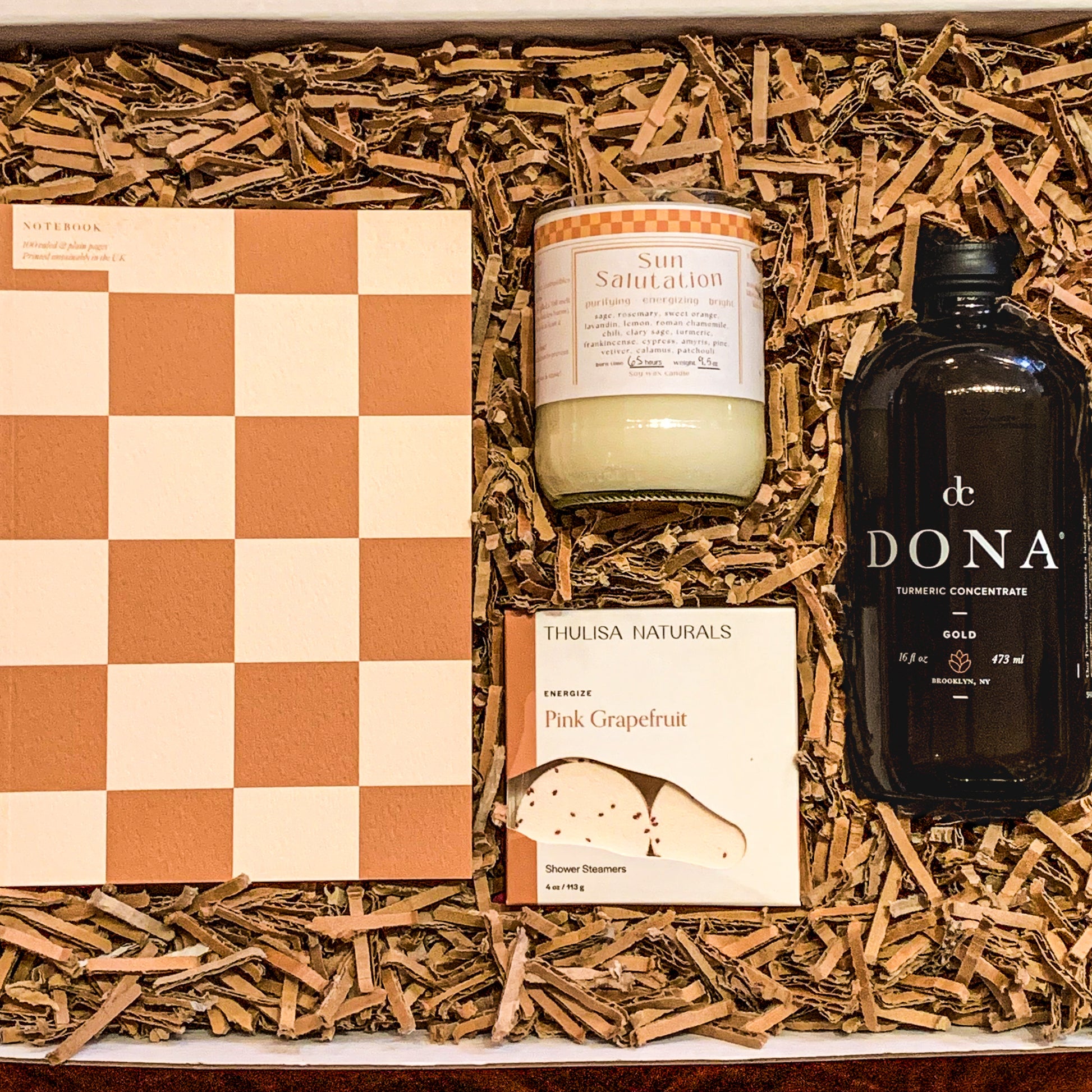 Eco-Friendly self care gift box with a checkered a5 notebook, a "sun salutation" candle, pink grapefruit shower steamers and a turmeric latte concentrate (16oz)