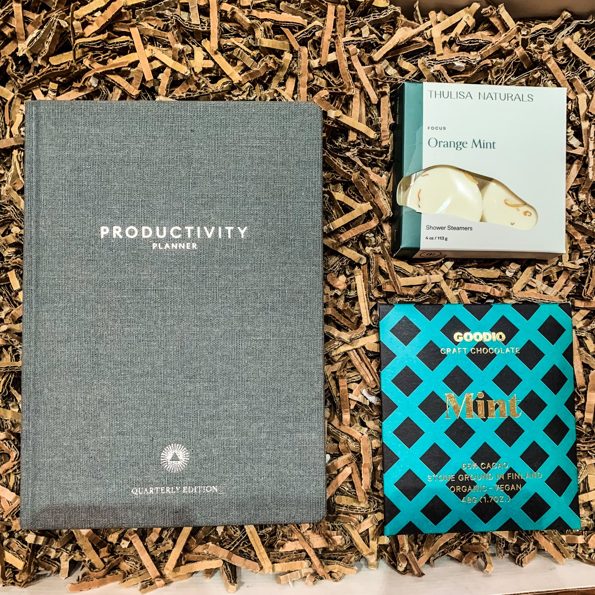 "Daily Productivity" office gift box overhead shot with a quarterly productivity planner, a vegan mint chocolate and orange mint essential oil shower steamers.