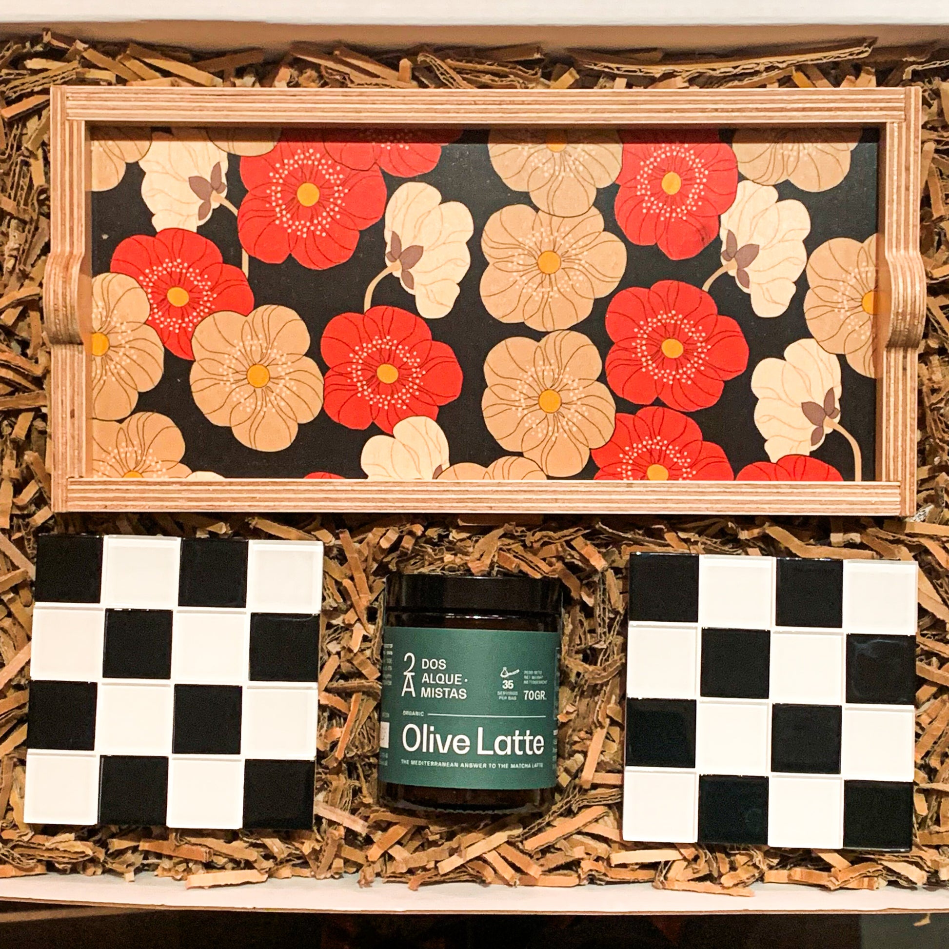 "Table for Two"eco-friendly gift box with an olive latte mix by Dos Alquemistas, a pair of black & white checkered tile coaster and a wooden decorative tray with large beige white and red poppies on a black background