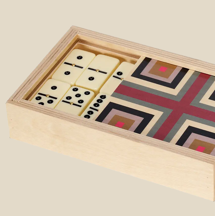 Close up of Wolfum Studio’s “Squaresville Maroon” Domino Set. The wooden box has a sliding top which is hale open to reveal the domino pieces inside.