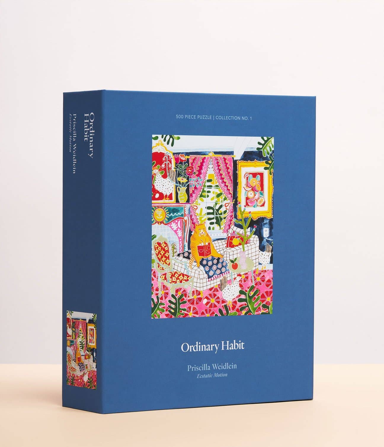 Display box of Ordinary Habit's "Ecstatic Motion" Puzzle. A blue box with the picture of the puzzle in the front depicting a fat cat lounging in a kitschy living room with a grid pattern couch and three chickens strolling through. Vibrant colors and maximalist decor. The box notes that this is a 500 piece puzzle illustrated by Priscilla Weidlein.